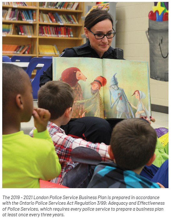 School Resource Officer reading a children's story book to a group of kids in school classroom