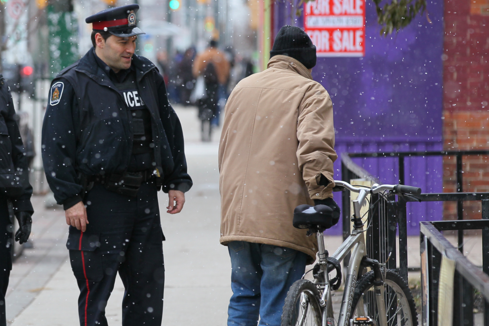 Officer walking, male walking bicycle on  sidewalk