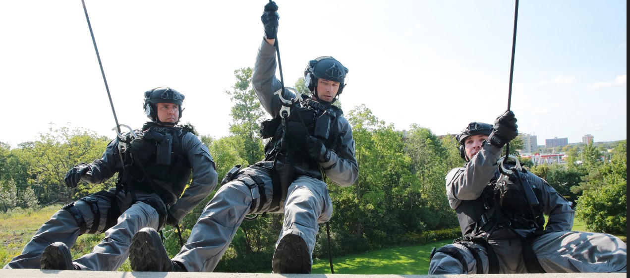 Three ERU members in tactical gear rappelling 