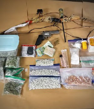 Drug paraphernalia, longbow, handgun, ammunition, baggies of pills 