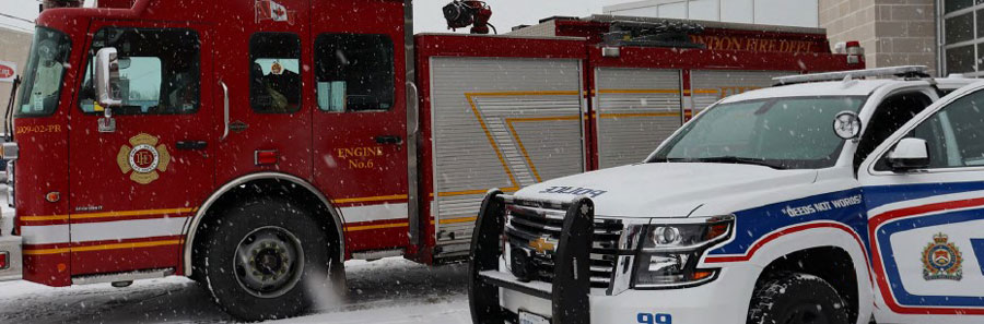 Fire truck and police SUV parked side by side, lightly snowing