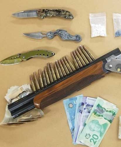 Knives, sawed off shotgun, ammunition, cash, drugs on table