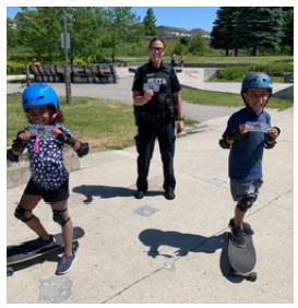 officer watching as two young kids skateboard