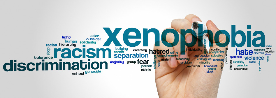hand holding a marker, word cloud containing xenophobia, racism, discrimination and other similar words