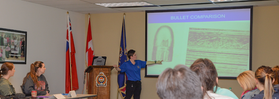 Citizens Academy classroom session, instructor discussing slide show on overhead monitor