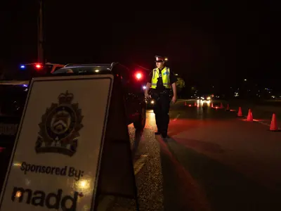 Night shot, Mothers Against Drunk Driving (MADD) sign, officer in reflective vest walking