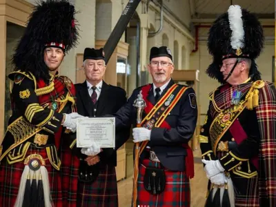 4 members of LPS Pipes and Drums, holding certificate