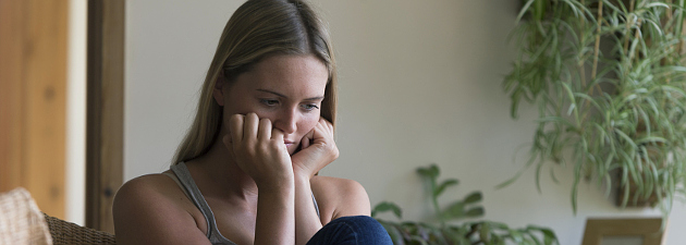 woman sitting in chair, holding her face in her hands