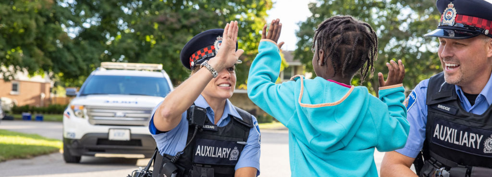 Female and male Auxiliary officers high fiving young girl