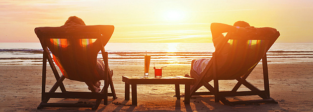 Couple relaxing in lounge chairs at sunset on beach