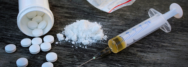 Illicit drugs on table - pills, white powder and syringe