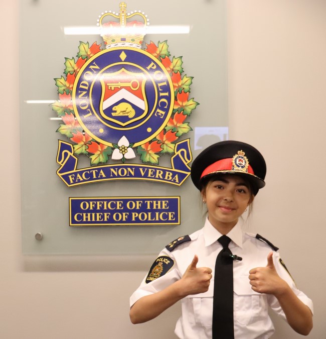 Female student in police uniform giving thumbs up