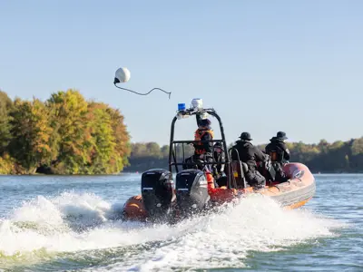 officer riding in LPS boat across lake, large wake from boat