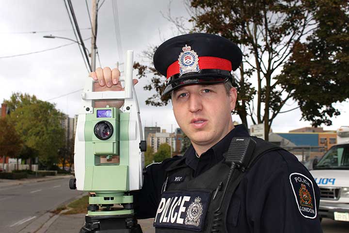 Traffic officer standing on side of roadway with collision reconstruction equipment