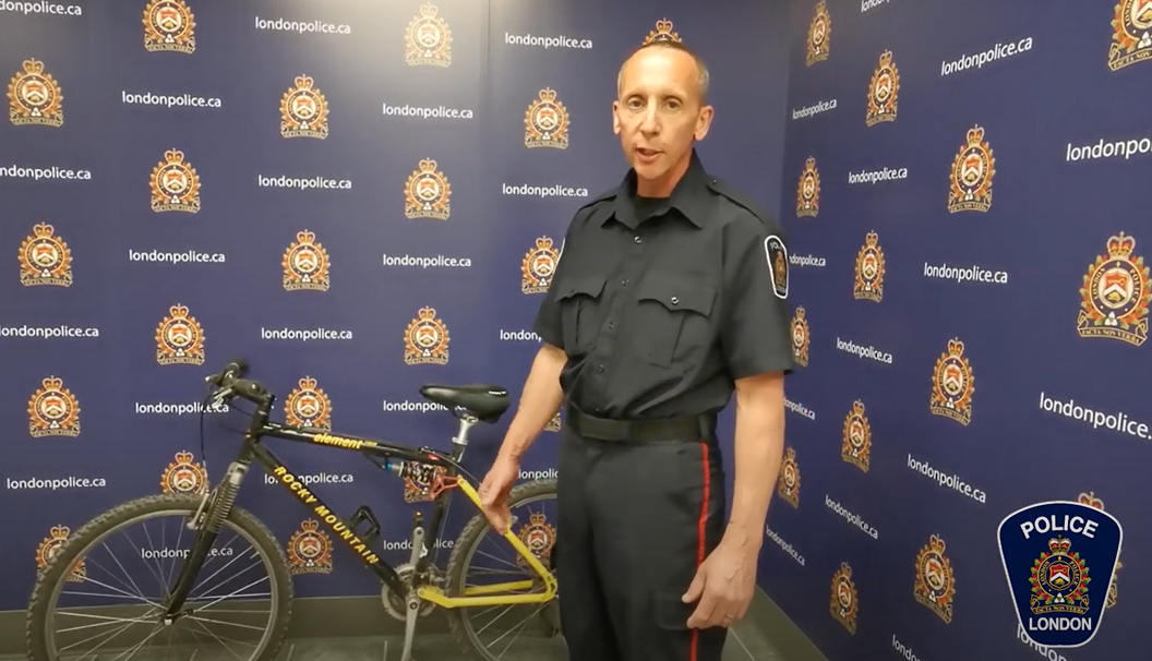 Officer Noel speaking and holding yellow mountain bike
