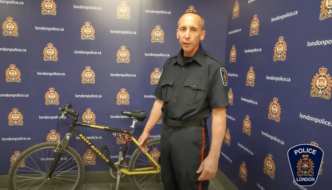 Officer Noel speaking and holding yellow mountain bike