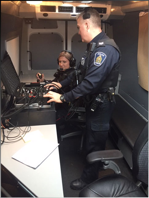 Male and female crisis negotiators in negotiators van operating voice recording equipment