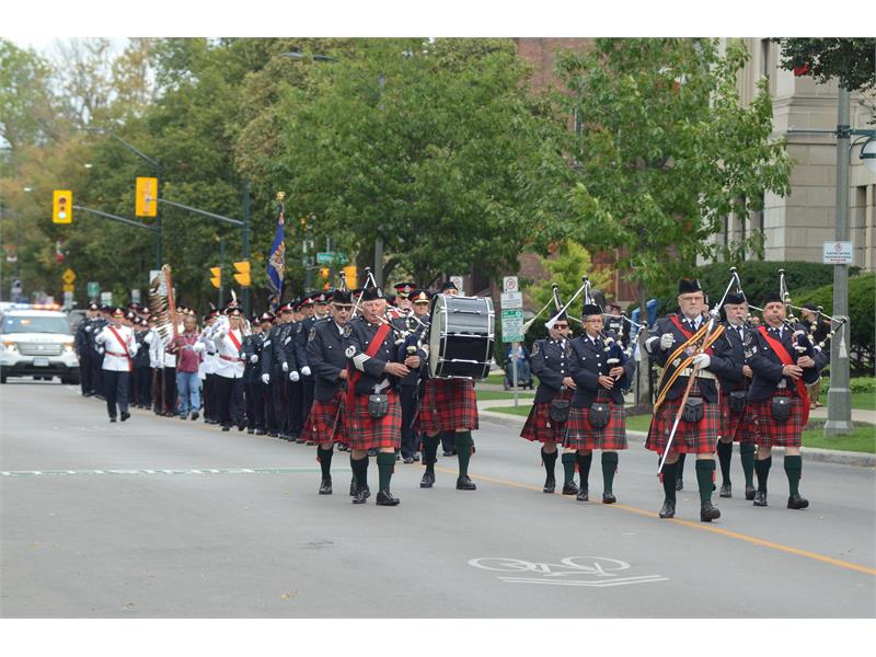 Pipes and Drums Band marching down middle of street