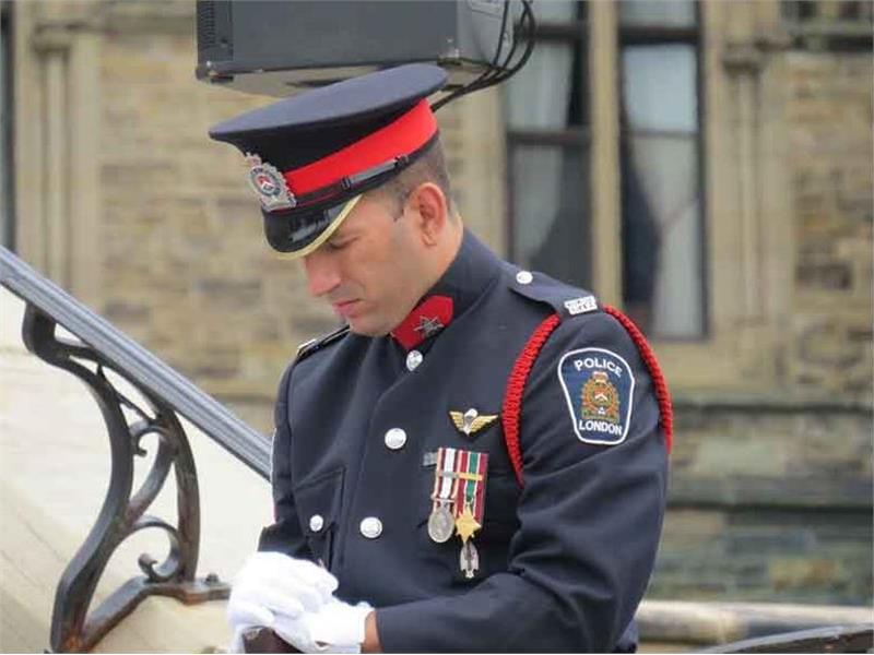 Lone officer, head down, eyes closed holding stock of rifle